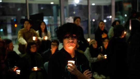 Demonstranten nehmen an einer Mahnwache bei Kerzenlicht teil.