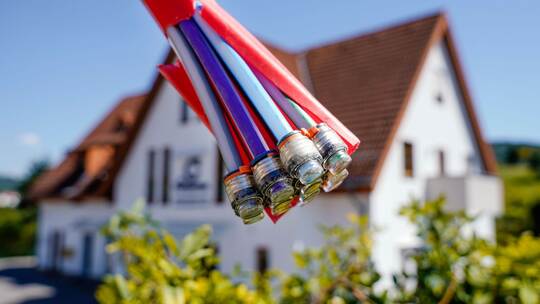 Bündel mit Umhüllungen für Glasfaserkabel vor einem Wohnhaus Bündel mit Umhüllungen für Glasfaserkabel vor einem Wohnhaus