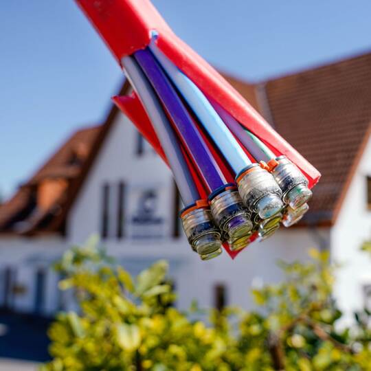 Bündel mit Umhüllungen für Glasfaserkabel vor einem Wohnhaus