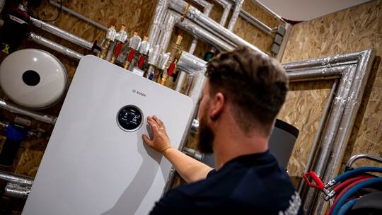 Handwerker zeigt an einer Wärmepumpe auf die Anzeige Handwerker zeigt an einer Wärmepumpe auf die Anzeige