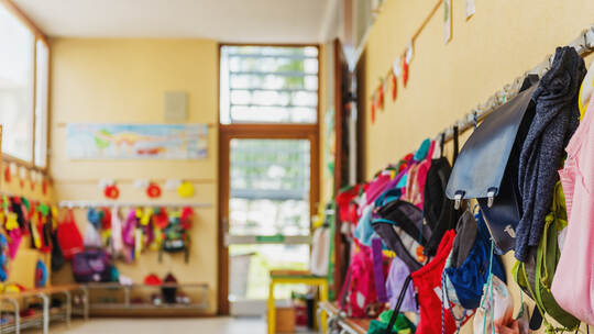 Empty hallway in the school, backpacks and bags on hooks, bright recreation room
