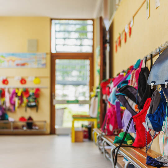 Empty hallway in the school, backpacks and bags on hooks, bright recreation room
