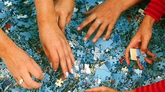 Hände greifen Puzzleteile