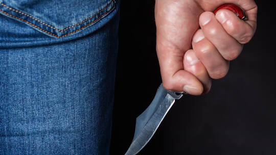 Man holding a knife in a threatening stance ready to fight
