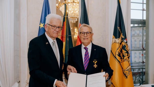 Ministerpräsident Winfried Kretschmann (links) überreicht die Urkunde an Wolfgang Scheidtweiler.