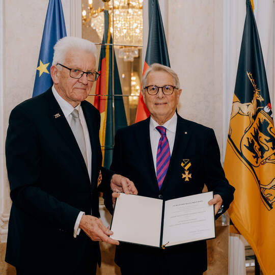 Ministerpräsident Winfried Kretschmann (links) überreicht die Urkunde an Wolfgang Scheidtweiler.