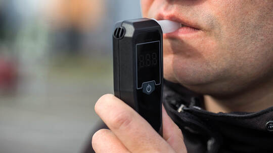 Male Driver Using Personal Alcometer For Sobriety Check. Man Exhaling Into Alcohol Test Device. Driving license revocation for a