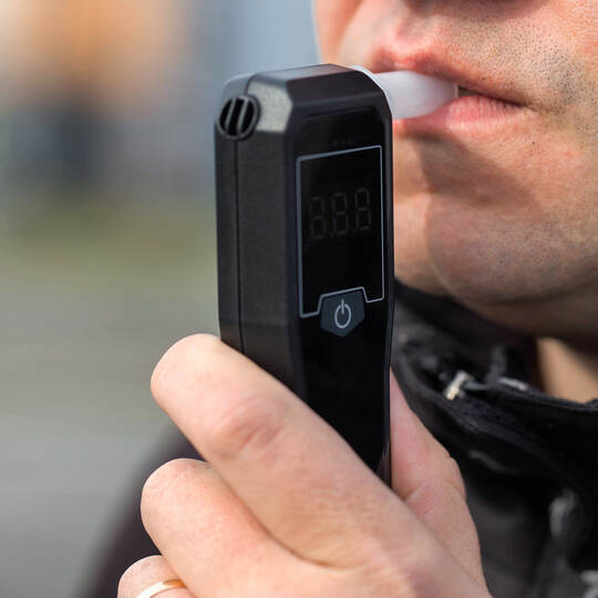 Male Driver Using Personal Alcometer For Sobriety Check. Man Exhaling Into Alcohol Test Device. Driving license revocation for a