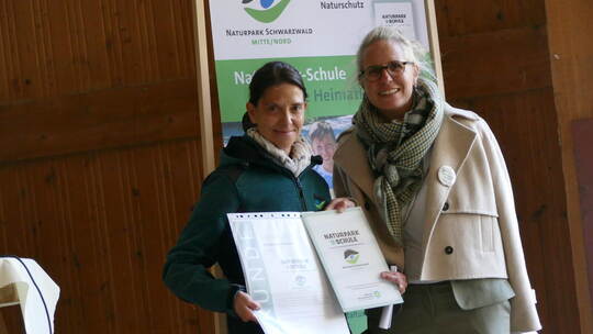 Yvonne Flesch vom Naturpark Schwarzwald Mitte/Nord (links) überreicht Schulleiterin Elisabeth Kiebelstein die Urkunde. Fux