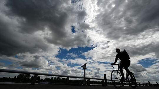 Radfahrer unter Wolkenhimmel