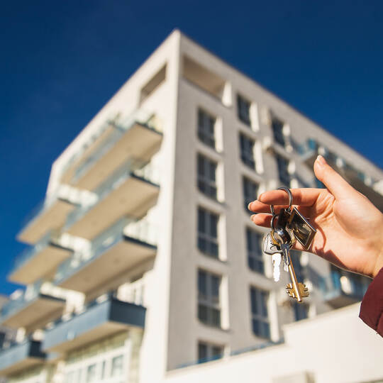 The concept of buying a new apartment. The woman hand holds the keys to a new apartment