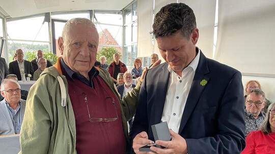 Bürgermeister Matthias Stepan übergibt die silberne Münze an Wolfgang Obert.