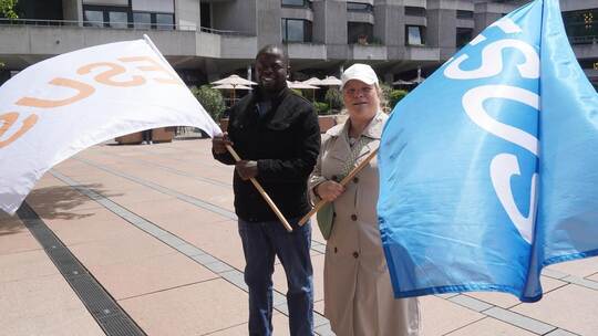 Pastor Stéphane Tchangang und Koordinatorin Silke Vierhock von der evangelisch-freikirchlichen Gemeinde stehen mit den Fahnen do