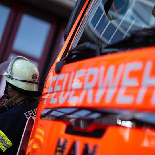 Feuerwehrmann steht neben einem Feuerwehrauto (Symbolbild)