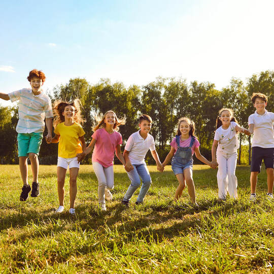Group of a happy smiling kids friends having fun and jumping in the park standing in a line.