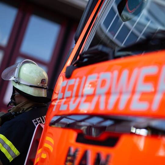 Feuerwehrmann steht neben einem Feuerwehrauto (Symbolbild)