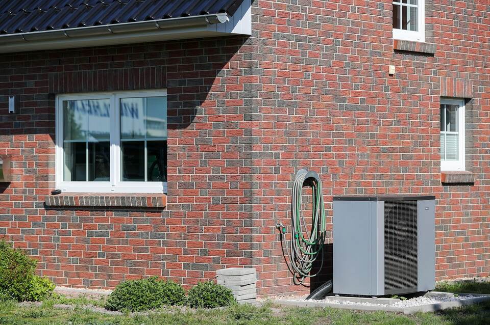 Eine Luft-Wasser-Wärmepumpe steht vor einem Haus Eine Luft-Wasser-Wärmepumpe steht vor einem Haus