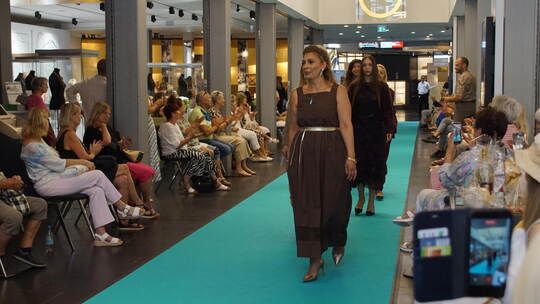 Bei der großen Modenschau präsentieren die Models auf einem türkisgrünen Teppich Styles vom Modehaus Jung und edles Geschmeide.