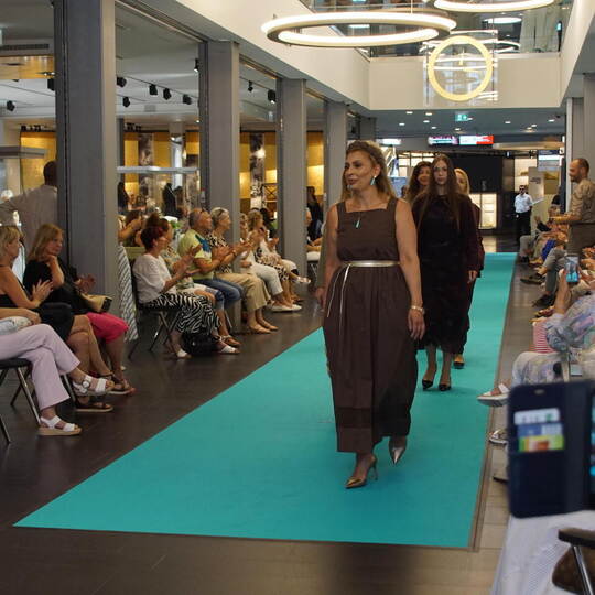 Bei der großen Modenschau präsentieren die Models auf einem türkisgrünen Teppich Styles vom Modehaus Jung und edles Geschmeide.