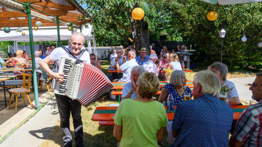 Beste Stimmung beim Gartenfest: Musiker Hans Pfeil spielt mit seinem Akkordeon Wunschlieder der Gäste.