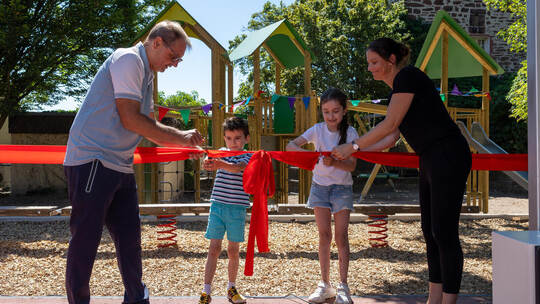 Das rote Band zur offiziellen Eröffnung des neuen Spielplatzes der Schlossparkschule wird von den Schülern Alessio und Alina mit