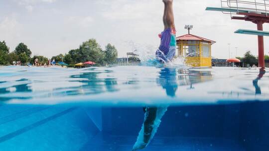 Schwimmer springt vom Sprungturm ins Wasser Schwimmer springt vom Sprungturm ins Wasser