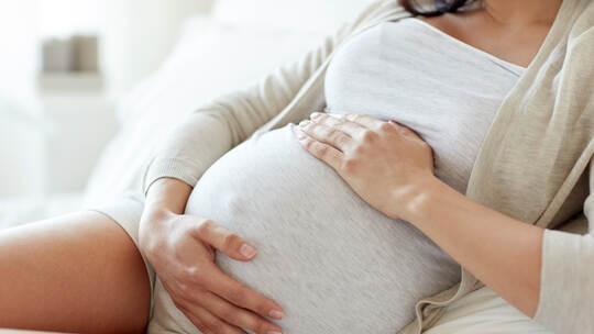 close up of pregnant woman lying in bed at home
