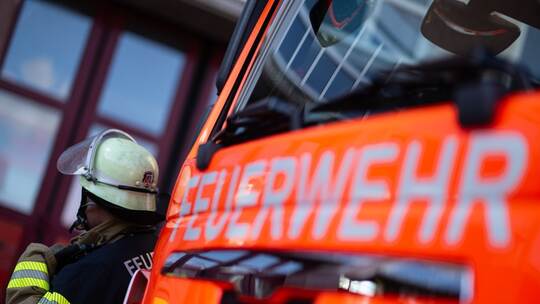 Feuerwehrmann steht neben einem Feuerwehrauto (Symbolbild) Feuerwehrmann steht neben einem Feuerwehrauto (Symbolbild)