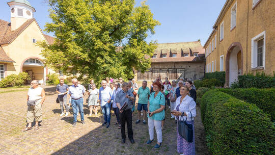 Weiter geht es in den Ehrenhof, der von einer mächtigen Linde dominiert wird und den Blick auf das Herrenhaus, die Stallungen un