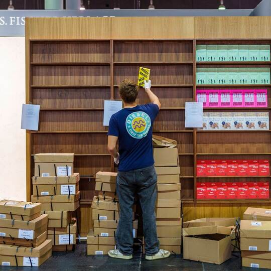 Ein junger Mann räumt Bücher in ein Regal ein