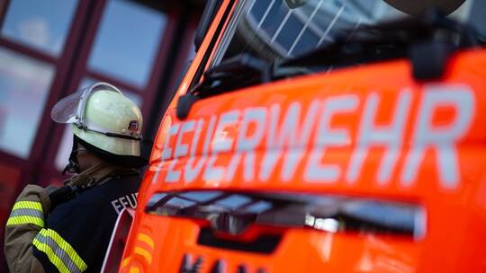 Feuerwehrmann steht neben einem Feuerwehrauto (Symbolbild)