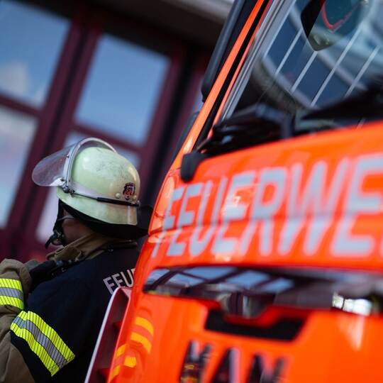 Feuerwehrmann steht neben einem Feuerwehrauto (Symbolbild)