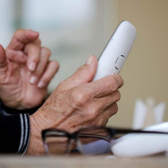 Rentner hält Telefon in der Hand