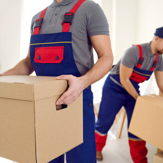 Male movers with boxes unload client belongings