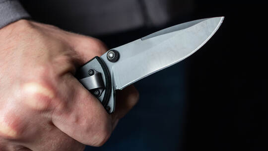 Man holding a knife in a threatening stance ready to fight
