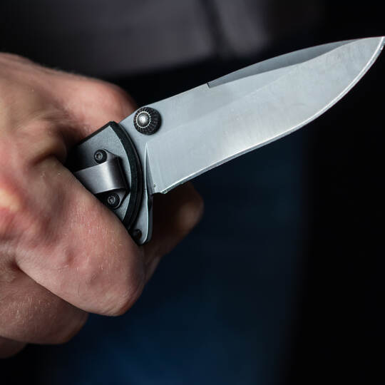 Man holding a knife in a threatening stance ready to fight