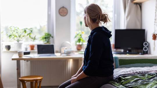 Eine Studentin sitzt auf dem Bett in ihrem WG-Zimmer Eine Studentin sitzt auf dem Bett in ihrem WG-Zimmer