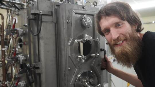 Herzstück: Fabian Seifried mit der Maschine, die das Beschichten von Oberflächen mithilfe der PVD-Technologie ermöglicht. Nico r