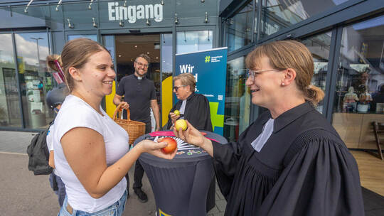 Marcia Beer (links) erhält von den Geistlichen Florian Binsch, Heike Reisner-Baral und Susanne Bräutigam einen Apfel. Pop-Up Kirche Edeka Huchenfeld