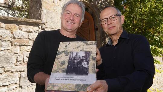 Pfarrer Markus Mall (links) und Markus Ziegler präsentieren das Ortsfamilienbuch, das sie gemeinsam erstellt haben. Auf mehr als