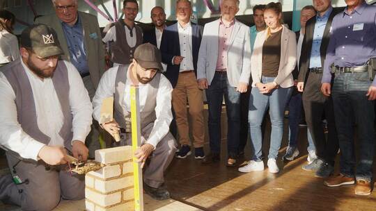 Bei der Bau-Innung Pforzheim-Enzkreis zeigen zwei engagierte Auszubildende, wie eine Mauer entsteht. Auch Organisator Christian