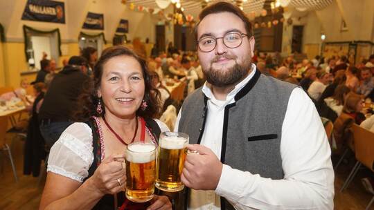 Zur Eröffnung des Trachtenabends stoßen die Vorsitzende Ute Fischer und Dirigent Sascha Widmann in der bayerisch geschmückten Ha