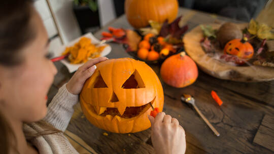 Beautiful young woman cutting a pumpkin for Halloween