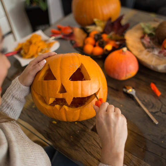 Beautiful young woman cutting a pumpkin for Halloween