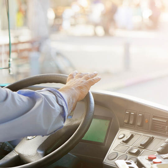 cropped shot of bus driver holding steering whee