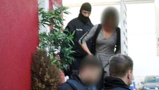 Polizisten führen in Bonn eine Person ab: Mehr als 100 Personen wurden bei der bundesweiten Aktion gegen eine Bande im R