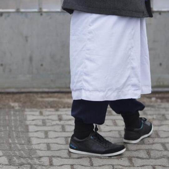 Ein Mann in traditioneller Bekleidung steht vor einem Versammlungsort der Salafisten in Berlin. Foto: Florian Schuh/dpa