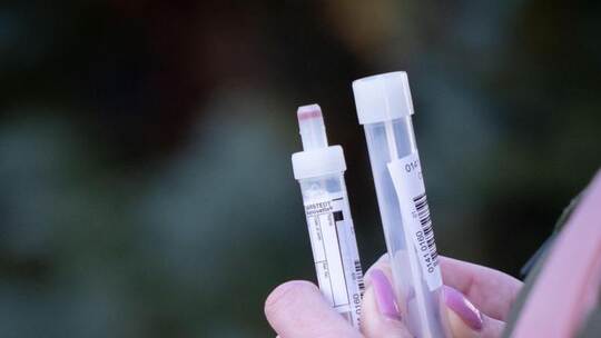 Eine steht wartend vor einem Zelt für den Coronatest in Berlin-Lübars mit Teströhrchen. Foto: Kay Nietfeld/dpa Eine steht wartend vor einem Zelt für den Coronatest in Berlin-Lübars mit Teströhrchen. Foto: Kay Nietfeld/dpa