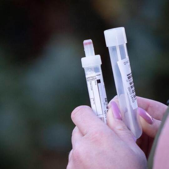 Eine steht wartend vor einem Zelt für den Coronatest in Berlin-Lübars mit Teströhrchen. Foto: Kay Nietfeld/dpa Eine steht wartend vor einem Zelt für den Coronatest in Berlin-Lübars mit Teströhrchen. Foto: Kay Nietfeld/dpa