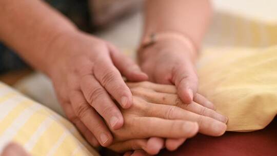 Eine Hospizmitarbeiterin hält die Hand eines todkranken Menschen, der im Hospiz im Bett liegt. Foto: Felix Kästle/dpa Eine Hospizmitarbeiterin hält die Hand eines todkranken Menschen, der im Hospiz im Bett liegt. Foto: Felix Kästle/dpa